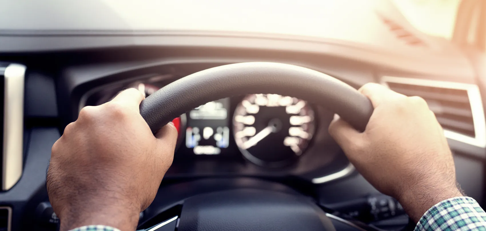 Bestuurder met beide handen aan het stuur van de auto, tijdens de rijles voor het aanhangerrijbewijs (BE)