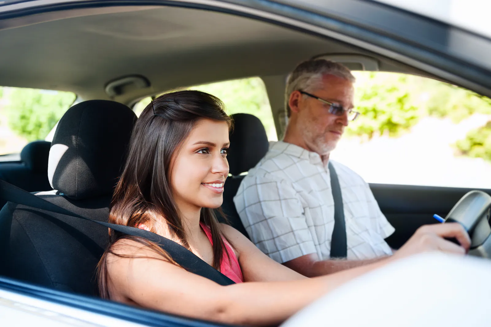 Lachende leerling achter het stuur van de lesauto, met naast haar de rij-instructeur tijdens de rijles