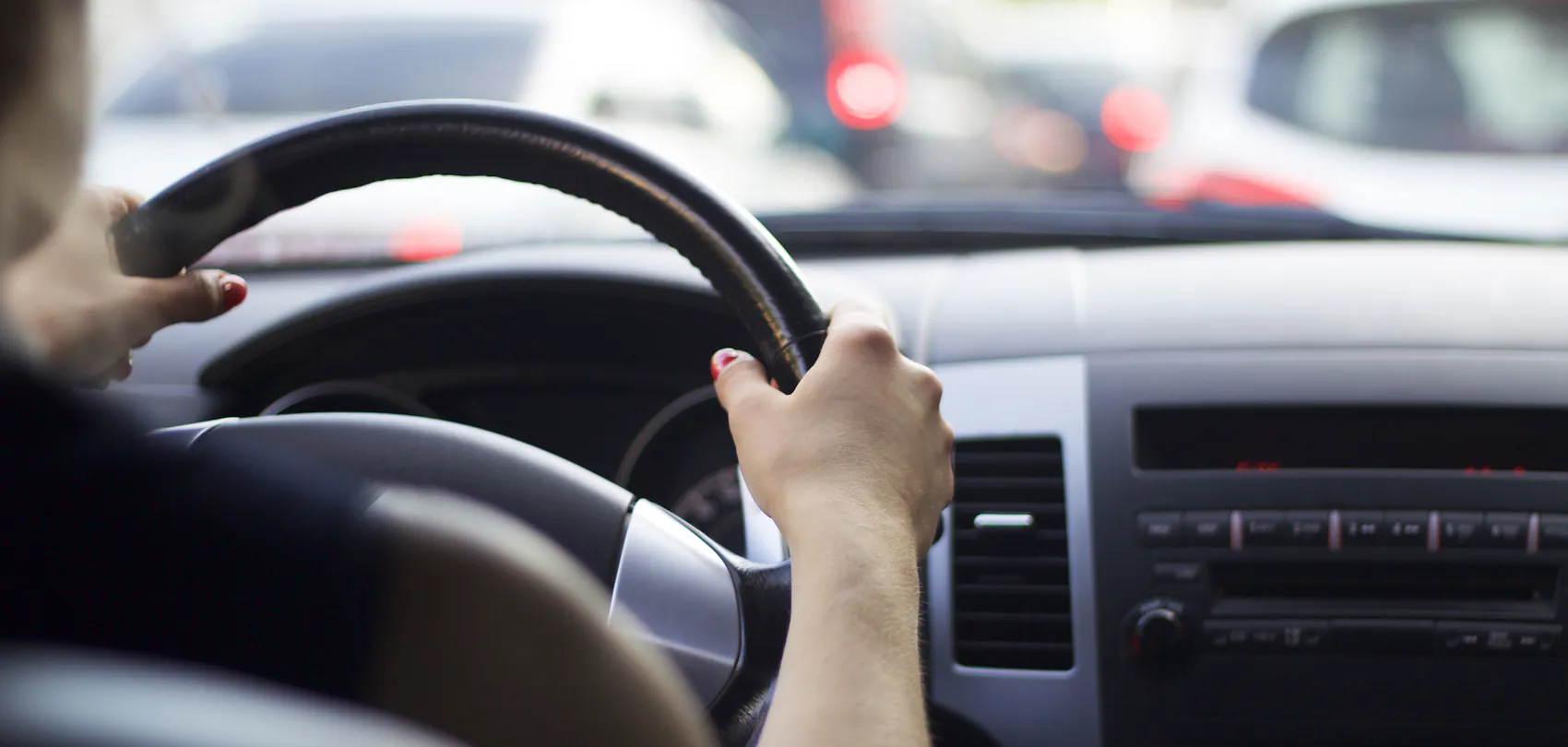 Chauffeur met de handen aan het stuur in het stadsverkeer, tijdens de opleiding tot taxichauffeur