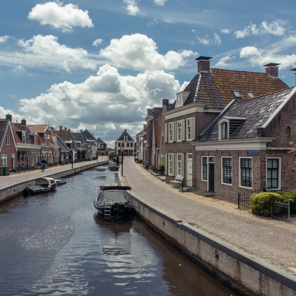 Een vaart met traditionele huizen in Kollum, waar je de rijscholen in Kollum kunt vergelijken