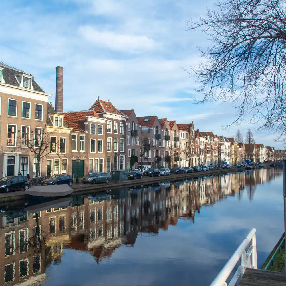 Een gracht met historische huizen in Leiden: vergelijk de rijscholen in Leiden